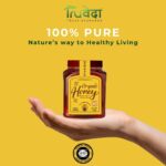 Hand holding a jar of Truveda organic honey labeled 100% pure, promoting healthy living through natural sweetener from Khadi India