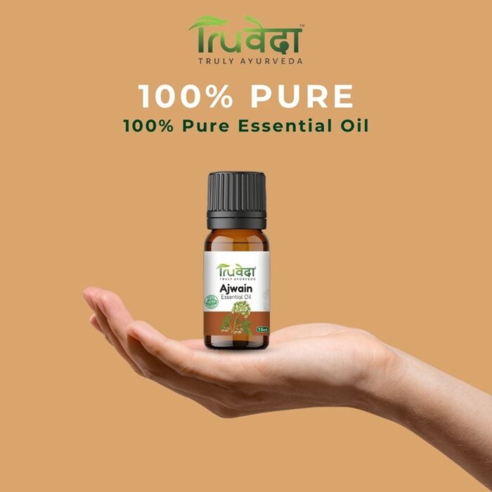 Hand holding a bottle of Truveda Ajwain essential oil, made from carom seeds, labeled 100% pure for aromatherapy, massage, and wellness
